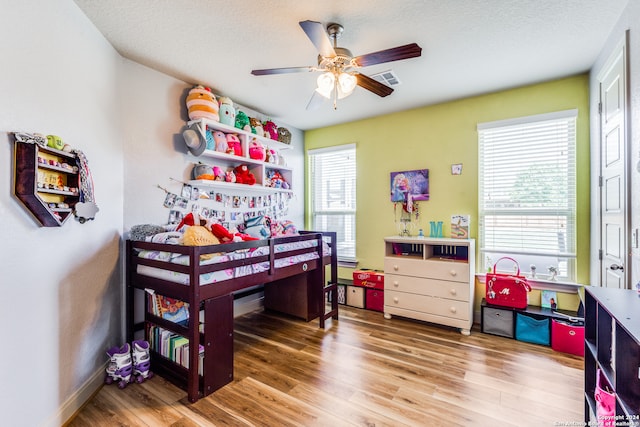 bedroom with multiple windows, a textured ceiling, hardwood / wood-style flooring, and ceiling fan