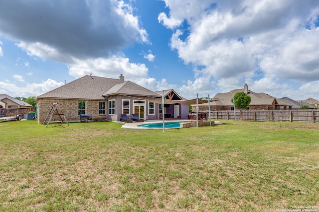 rear view of property with a patio, a lawn, and a fenced in pool