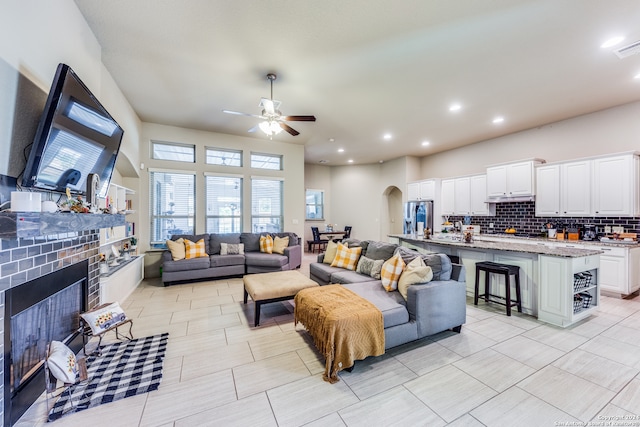 tiled living room featuring a fireplace and ceiling fan