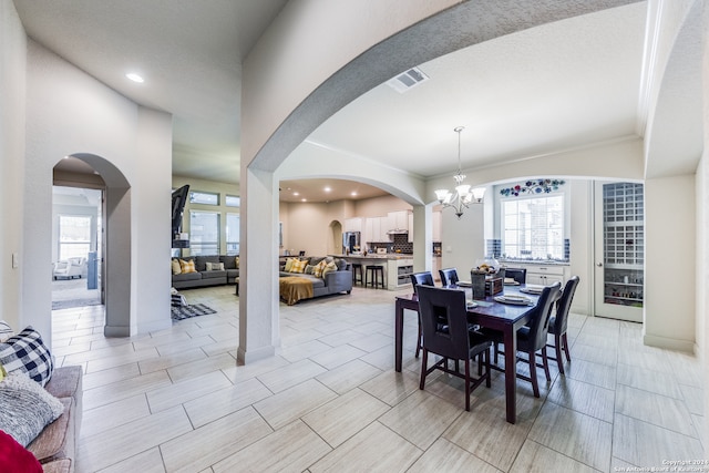 dining space featuring an inviting chandelier, crown molding, and light tile patterned flooring