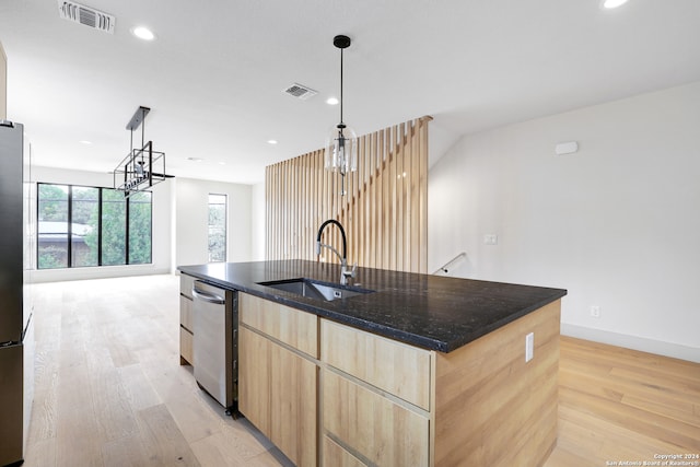 kitchen featuring light brown cabinetry, decorative light fixtures, sink, a kitchen island with sink, and light hardwood / wood-style flooring