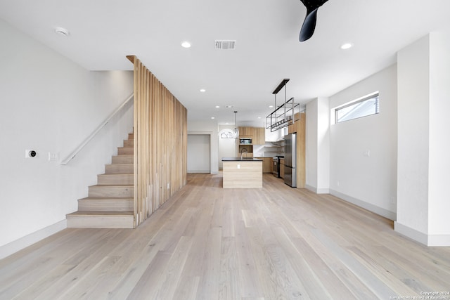 unfurnished living room with sink, ceiling fan, and light hardwood / wood-style flooring