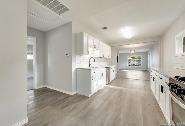 kitchen featuring white cabinetry, light wood-type flooring, tasteful backsplash, and stainless steel appliances