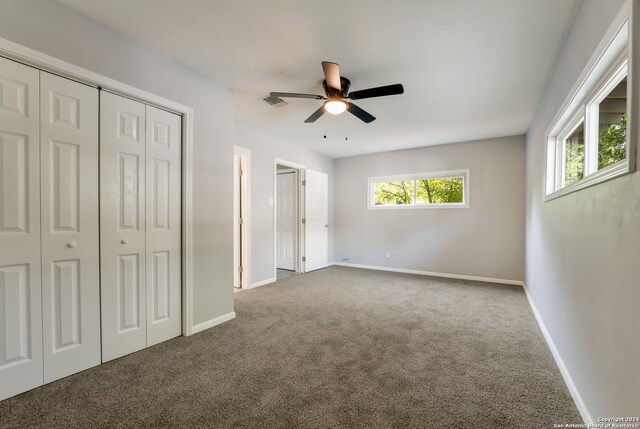 unfurnished bedroom featuring multiple windows, carpet, and ceiling fan