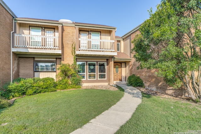 view of front of house with a front lawn and a balcony