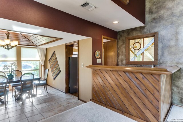 tiled dining area featuring a notable chandelier and wood ceiling