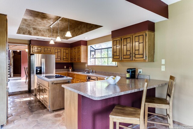 kitchen featuring pendant lighting, a tray ceiling, stainless steel fridge, sink, and kitchen peninsula