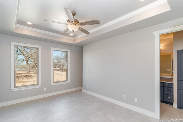 spare room featuring crown molding, ceiling fan, and a raised ceiling