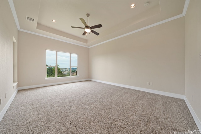 carpeted spare room with crown molding, a tray ceiling, and ceiling fan