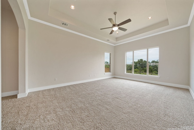 carpeted empty room featuring crown molding, a tray ceiling, and ceiling fan