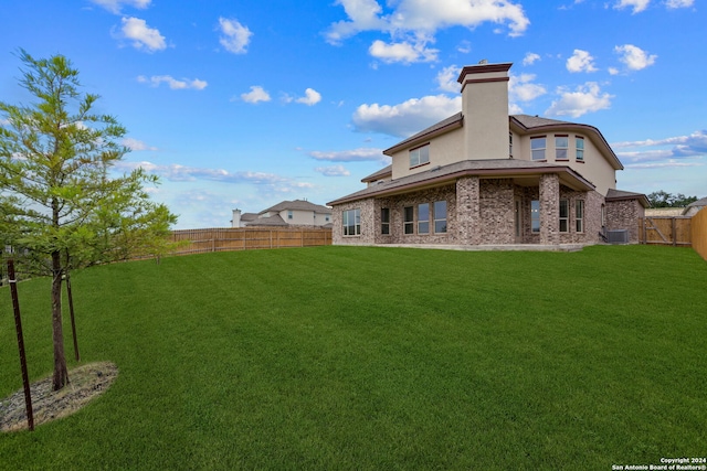 rear view of property featuring cooling unit and a yard