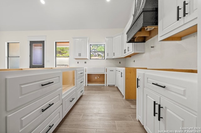 kitchen featuring custom exhaust hood, white cabinets, and light hardwood / wood-style floors