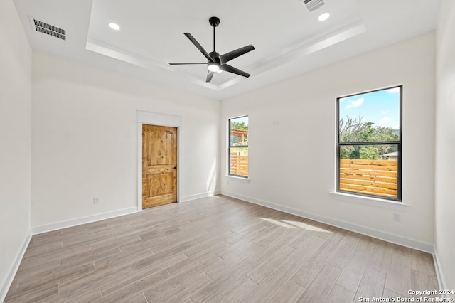 unfurnished bedroom featuring a raised ceiling, light hardwood / wood-style flooring, and ceiling fan