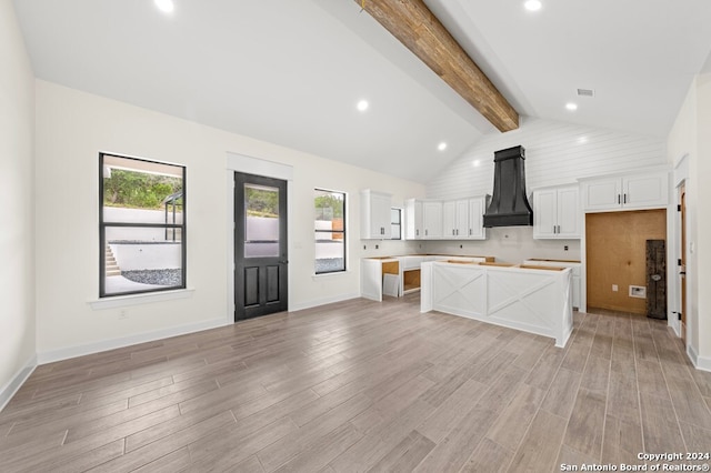 kitchen featuring beamed ceiling, white cabinets, premium range hood, light wood-type flooring, and a center island