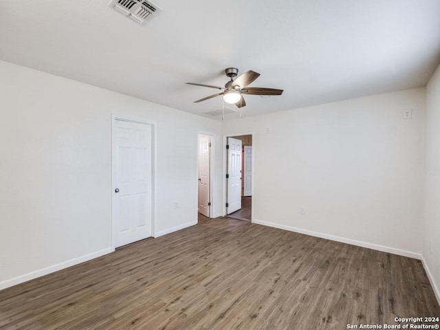 empty room with ceiling fan and dark hardwood / wood-style flooring