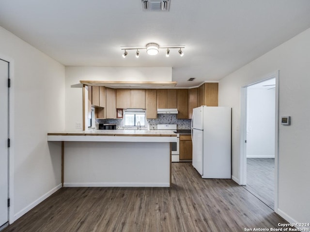 kitchen featuring tasteful backsplash, white appliances, kitchen peninsula, and hardwood / wood-style floors