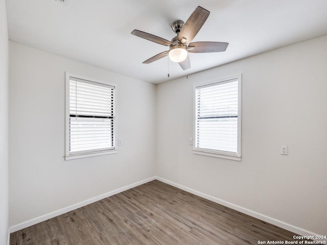 spare room with ceiling fan, a wealth of natural light, and dark hardwood / wood-style flooring