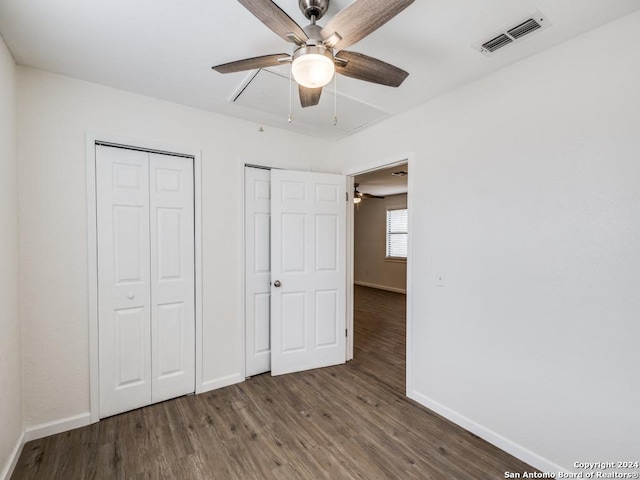 unfurnished bedroom featuring dark hardwood / wood-style floors, two closets, and ceiling fan