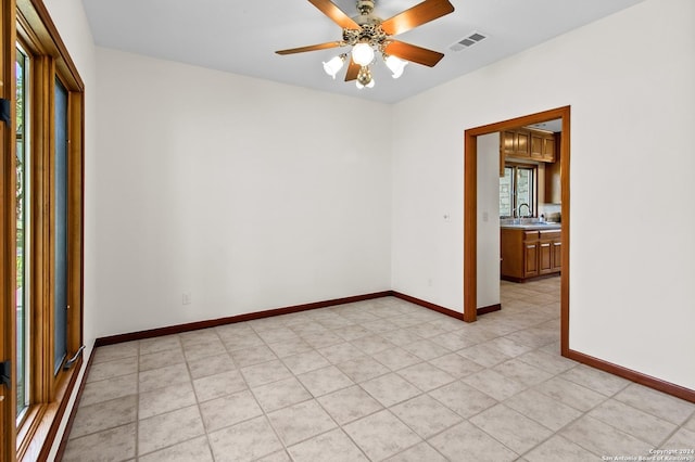 spare room with visible vents, baseboards, a sink, and a ceiling fan