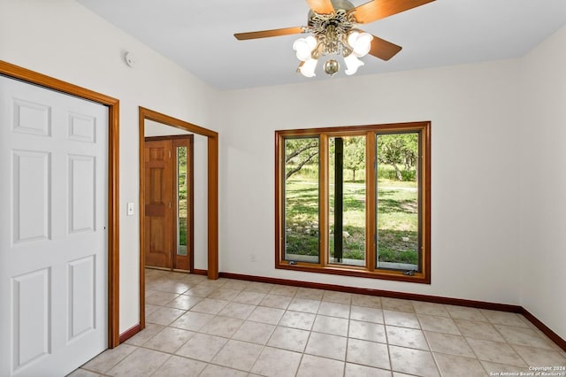interior space with ceiling fan, baseboards, and light tile patterned floors