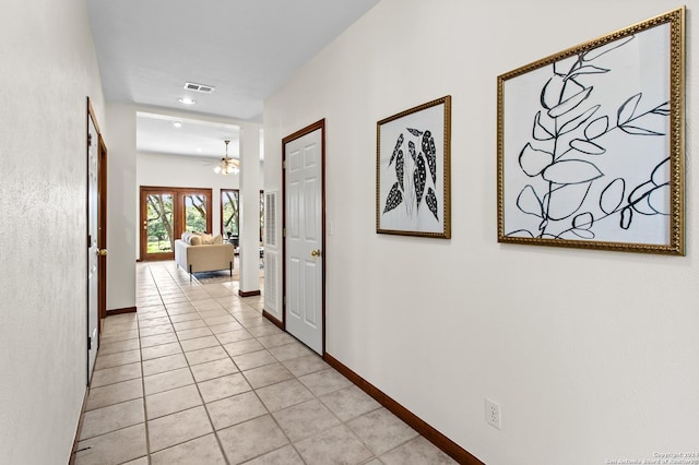 hallway featuring visible vents, baseboards, and light tile patterned flooring