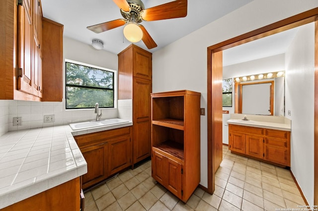kitchen featuring brown cabinetry, tasteful backsplash, a sink, and tile counters