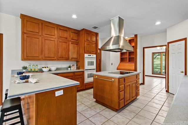 kitchen featuring island exhaust hood, a peninsula, light countertops, visible vents, and double oven