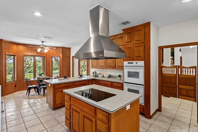 kitchen with white double oven, a peninsula, visible vents, island range hood, and black electric cooktop