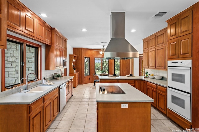 kitchen with a peninsula, visible vents, white double oven, island range hood, and a sink