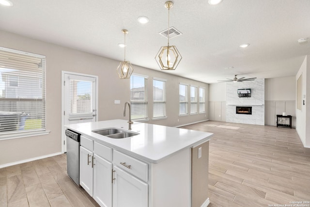 kitchen featuring white cabinets, an island with sink, dishwasher, pendant lighting, and sink