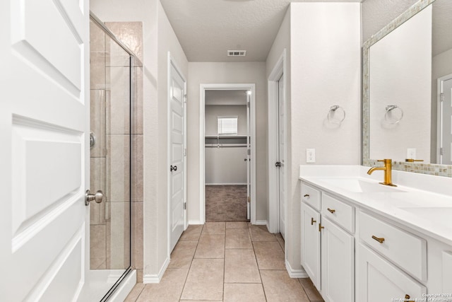 bathroom featuring vanity, a textured ceiling, tile patterned flooring, and an enclosed shower