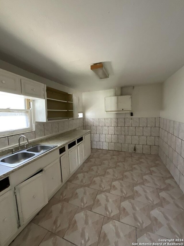 kitchen featuring tile walls, open shelves, light countertops, white cabinetry, and a sink