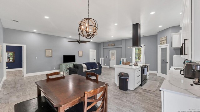 dining room with ceiling fan with notable chandelier and light hardwood / wood-style floors