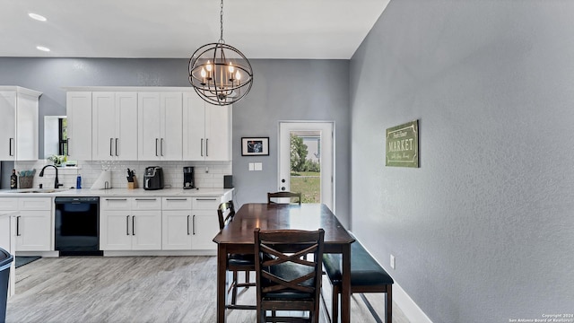 kitchen featuring pendant lighting, white cabinetry, black dishwasher, sink, and backsplash