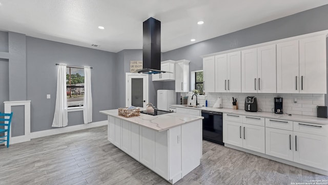 kitchen featuring a kitchen island, island range hood, white cabinetry, sink, and black appliances