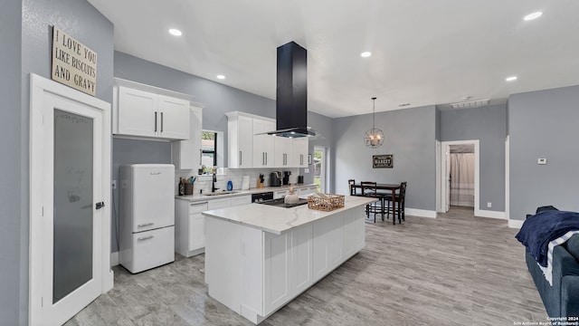 kitchen with light wood-type flooring, white cabinets, a kitchen island, light stone countertops, and island range hood