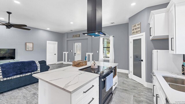 kitchen with a kitchen island, white cabinets, island exhaust hood, light stone counters, and electric stove