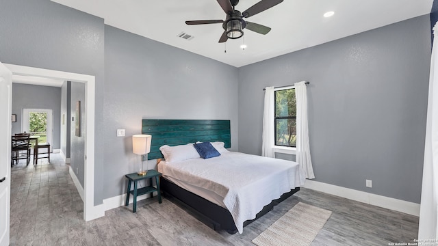 bedroom with ceiling fan, multiple windows, and hardwood / wood-style flooring