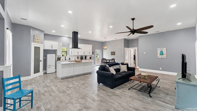 living room featuring sink, ceiling fan, and light wood-type flooring