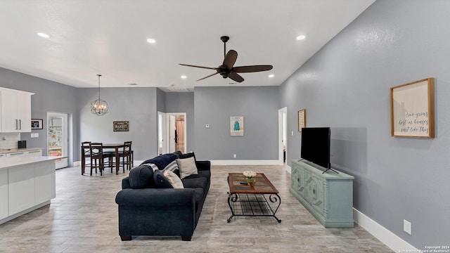 living room featuring ceiling fan with notable chandelier and light hardwood / wood-style flooring