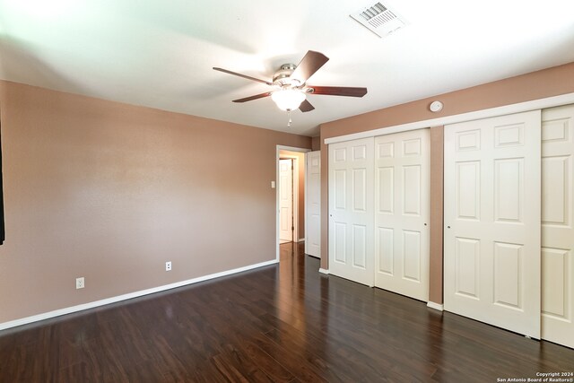 unfurnished bedroom featuring multiple closets, ceiling fan, and dark hardwood / wood-style floors