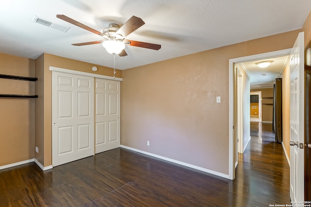 unfurnished bedroom featuring dark wood-type flooring, a textured ceiling, a closet, and ceiling fan