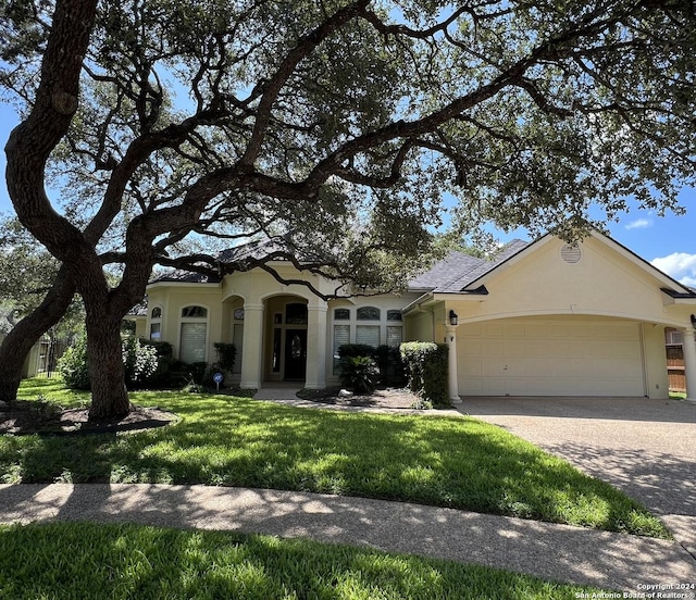 mediterranean / spanish home featuring a garage, decorative driveway, a front lawn, and stucco siding