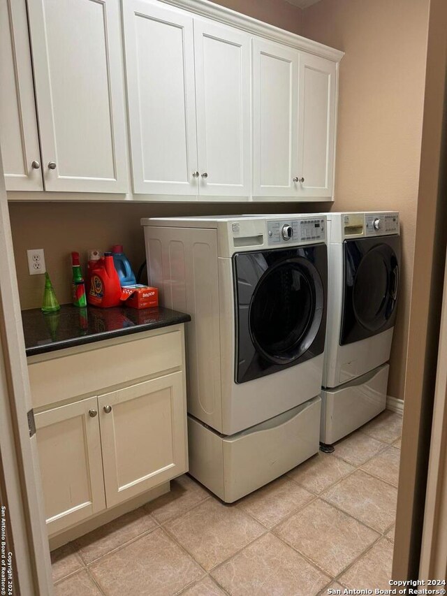 laundry area featuring cabinets, separate washer and dryer, and light tile patterned flooring