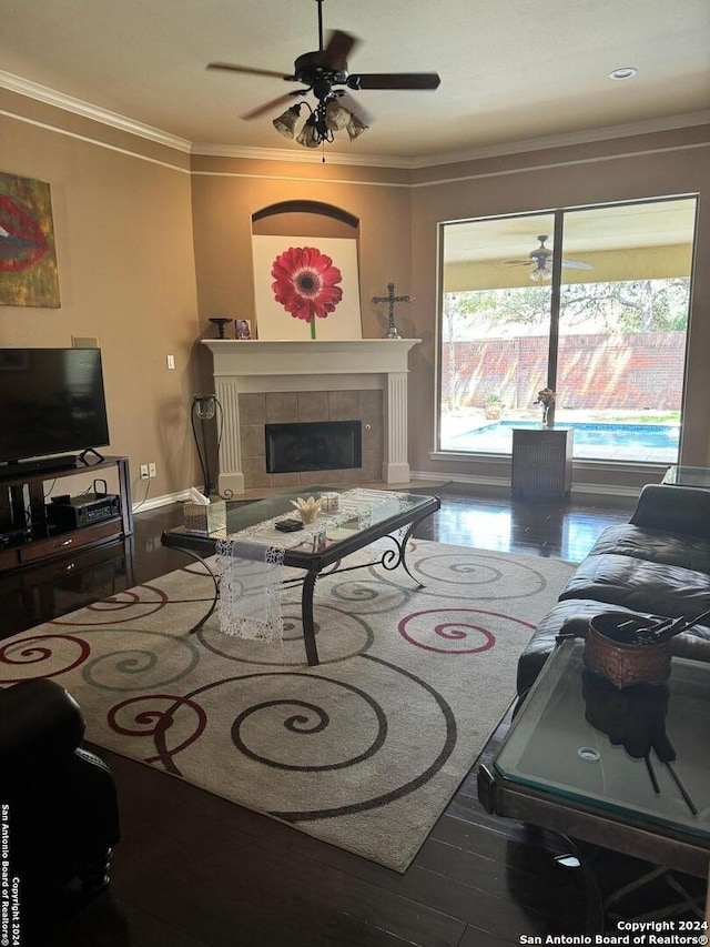 living room with ornamental molding, a tile fireplace, hardwood / wood-style flooring, and ceiling fan