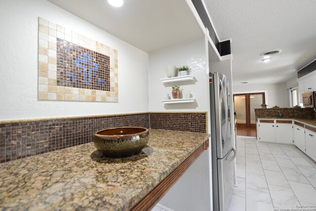 bar with decorative backsplash, stone counters, and light tile patterned floors