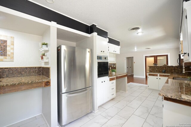 kitchen featuring light hardwood / wood-style flooring, stainless steel appliances, tasteful backsplash, white cabinets, and stone countertops