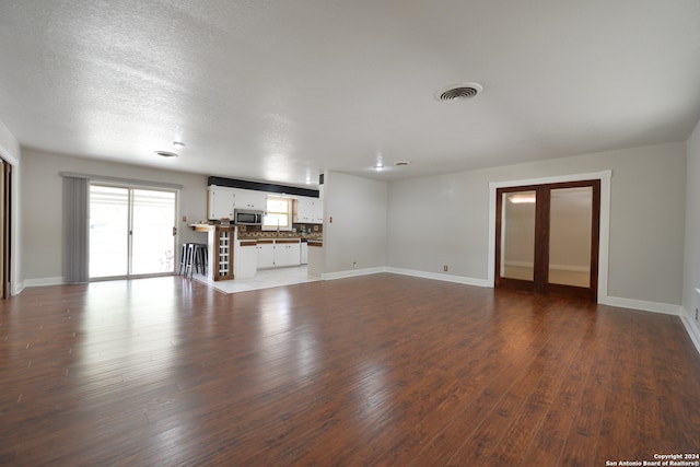 unfurnished living room with sink, a textured ceiling, and hardwood / wood-style floors