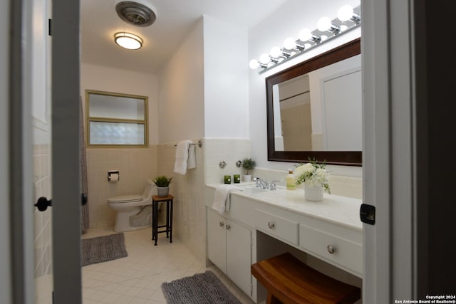 bathroom with vanity, tile patterned floors, toilet, and tile walls