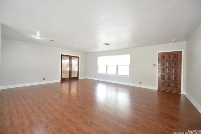 empty room with french doors, dark hardwood / wood-style flooring, and a textured ceiling